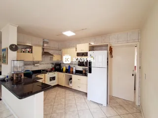 Foto interna de uma cozinha com armários claros e piso de cerâmica.