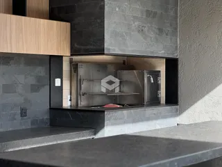 Uma seção da cozinha com eletrodomésticos de aço inoxidável e revestimento de pedra.