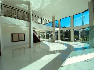 Vista interna de um espaço amplo com piso de alto brilho e grandes janelas.