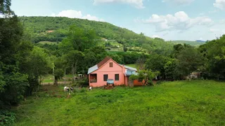 Foto da fachada de uma casa em uma área rural com colinas verdes ao fundo.