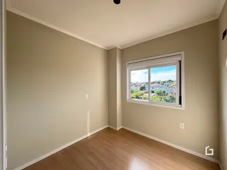 Ambiente interno de uma sala com piso de madeira e janela.
