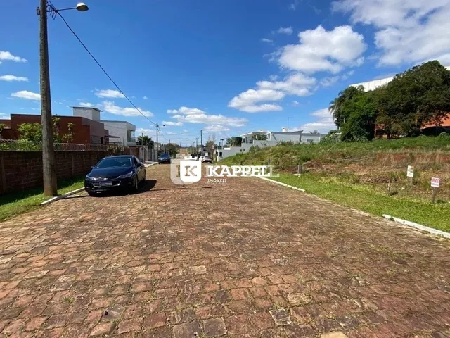 Vista da entrada de uma propriedade com pavimento de tijolos e vegetação ao ar livre.