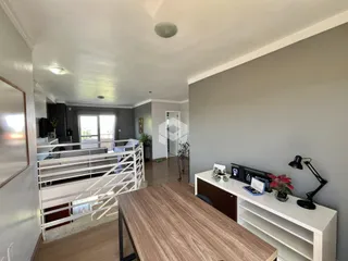 Vista de um corredor com escada e área de estar em um imóvel no Brasil.