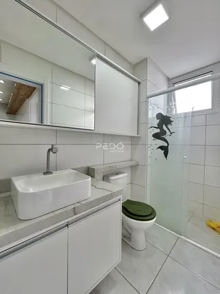 Interior de um banheiro moderno com revestimento cerâmico e box de vidro.