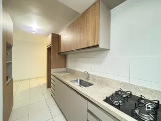 Cozinha com armários de madeira e piso cerâmico claro.