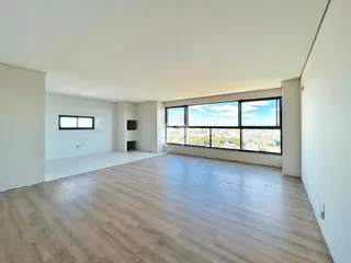 Uma sala de estar ampla com piso de madeira clara e grandes janelas.