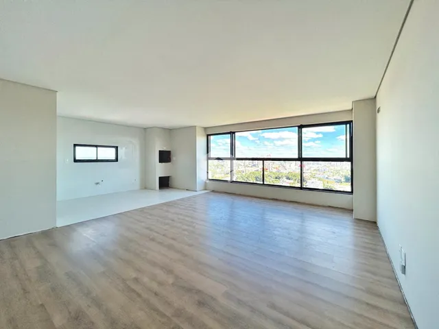 Uma sala de estar ampla com piso de madeira clara e grandes janelas.