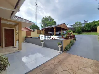 Vista externa da residência mostrando a área da piscina e o paisagismo.
