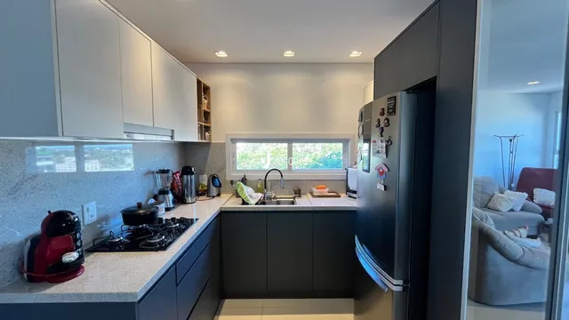 Foto de uma cozinha moderna com armários brancos e bancada clara.