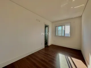 Interior de uma sala com piso de madeira escura e janela.