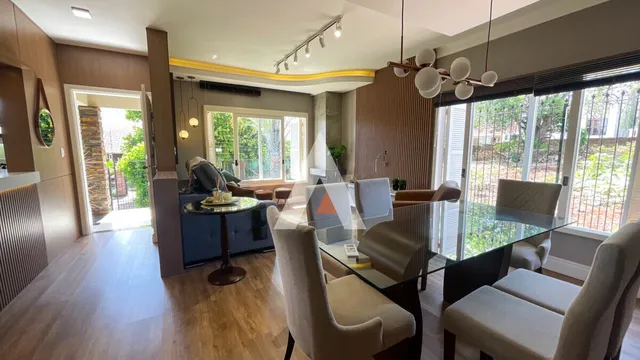 Sala de estar com piso de madeira e grandes janelas.