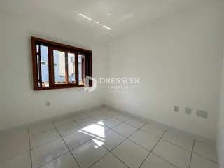 Interior de um cômodo com janela de madeira e piso de cerâmica branca.