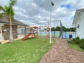 Área gramada com um playground e cerca no quintal.