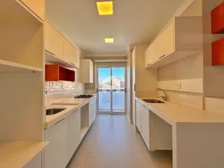 Cozinha moderna com armários brancos e piso claro.
