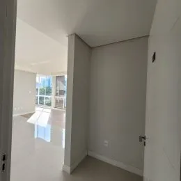 Hall de corredor interno com paredes brancas e piso claro.