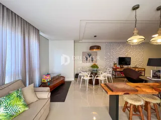 Sala de estar com cortinas claras e móveis de madeira.