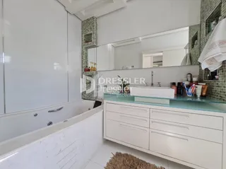 Foto do interior de um banheiro com banheira branca e revestimento de azulejos.