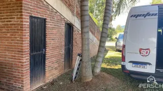 Parede externa de tijolos vermelhos com uma porta escura em uma propriedade.