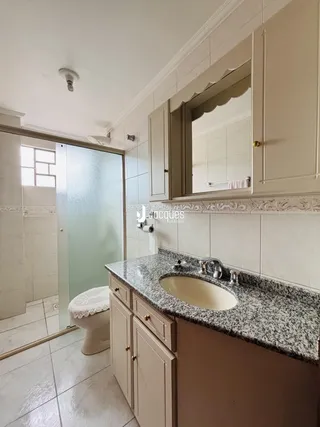 Vista de um banheiro com bancada e box de vidro.