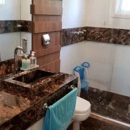 Foto de um banheiro com bancada de granito escuro e pia.