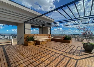 Vista panorâmica de uma área externa de madeira com mobiliário e estrutura de pérgola.