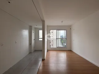 Vista de um corredor interno com piso de madeira e paredes brancas.