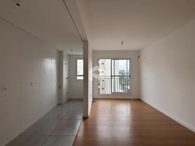 Vista de um corredor interno com piso de madeira e paredes brancas.