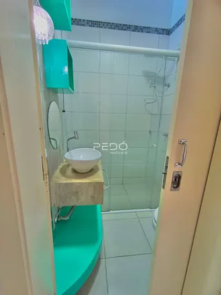 Foto de um banheiro com box de vidro e revestimento verde.