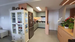 Uma cozinha moderna com armários brancos e madeira clara em um ambiente aberto.