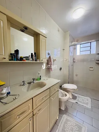 Foto de um banheiro com bancada e box de vidro.