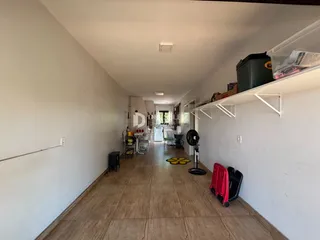 Corredor interno de uma residência com paredes brancas e piso de cerâmica.