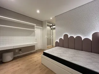 Quarto moderno com cabeceira estofada e piso de madeira clara.