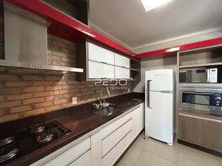 Esta é uma foto de uma cozinha moderna com armários brancos e bancadas escuras.