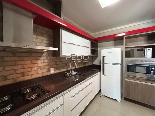 Esta é uma foto de uma cozinha moderna com armários brancos e bancadas escuras.