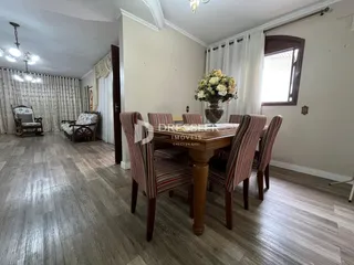 Sala de jantar com mesa de madeira e piso de madeira em uma residência.