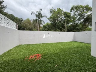 Vista externa de um quintal com gramado verde e muro branco em Lajeado.