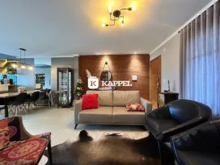 Sala de estar com sofá e poltronas em um ambiente com parede de madeira.