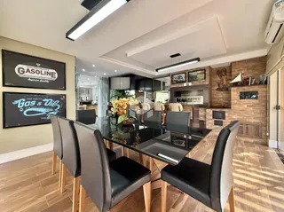 Uma sala de jantar com mesa escura e cadeiras em um ambiente moderno.