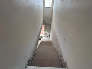 Corredor longo com piso de madeira e paredes brancas.