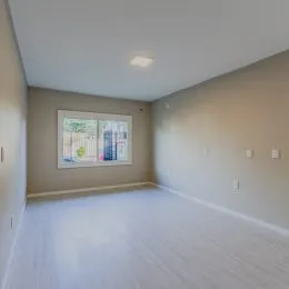 Foto de uma sala ampla com piso claro e janela.