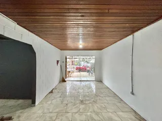 Corredor interno com piso de cerâmica e teto de madeira que leva a uma área externa.