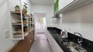 Cozinha com bancada escura e prateleiras de madeira.