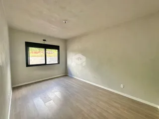 Ambiente interno de uma sala com piso de madeira clara e janela.