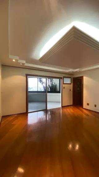 Sala de estar com piso de madeira polida e grande janela.
