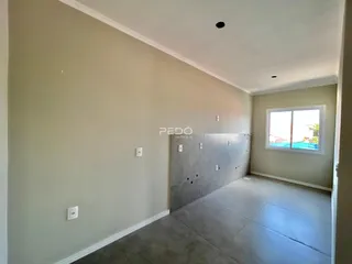Vista interna de um corredor com paredes claras e piso de concreto.