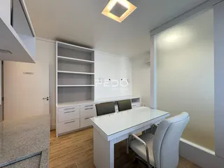 Uma sala de escritório com móveis brancos e piso de madeira clara.