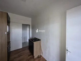 Ambiente interno de uma sala com piso de madeira e parede branca.