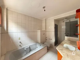 Banheiro com banheira e revestimento cerâmico nas paredes.