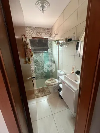 Foto de um banheiro com revestimento cerâmico e box de vidro.