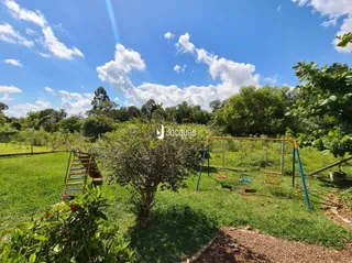 Vista de um campo gramado com vegetação e cerca em um ambiente externo.